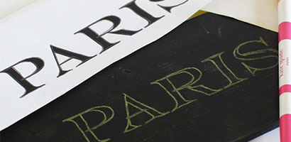 Black painted pine board with the word Paris printed on it from using transfer paper.