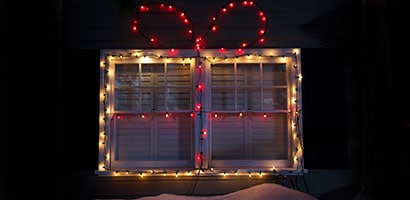Two exterior window panes decorated with white and red Christmas lights using Command™ light clips.